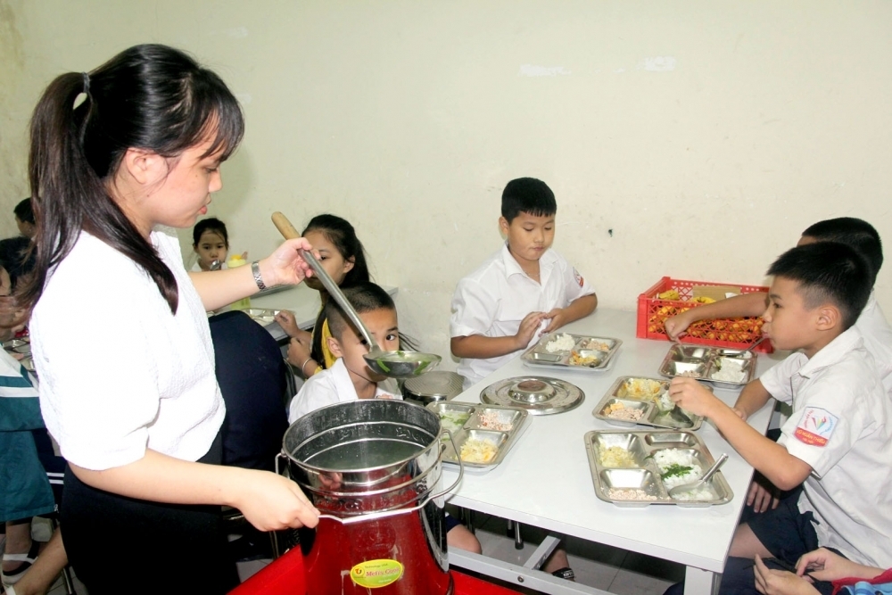 Giáo viên Trường Tiểu học Vũ Xuân Thiều (quận Long Biên, Hà Nội) hỗ trợ học sinh ăn trưa bán trú. (Ảnh minh họa M.K)