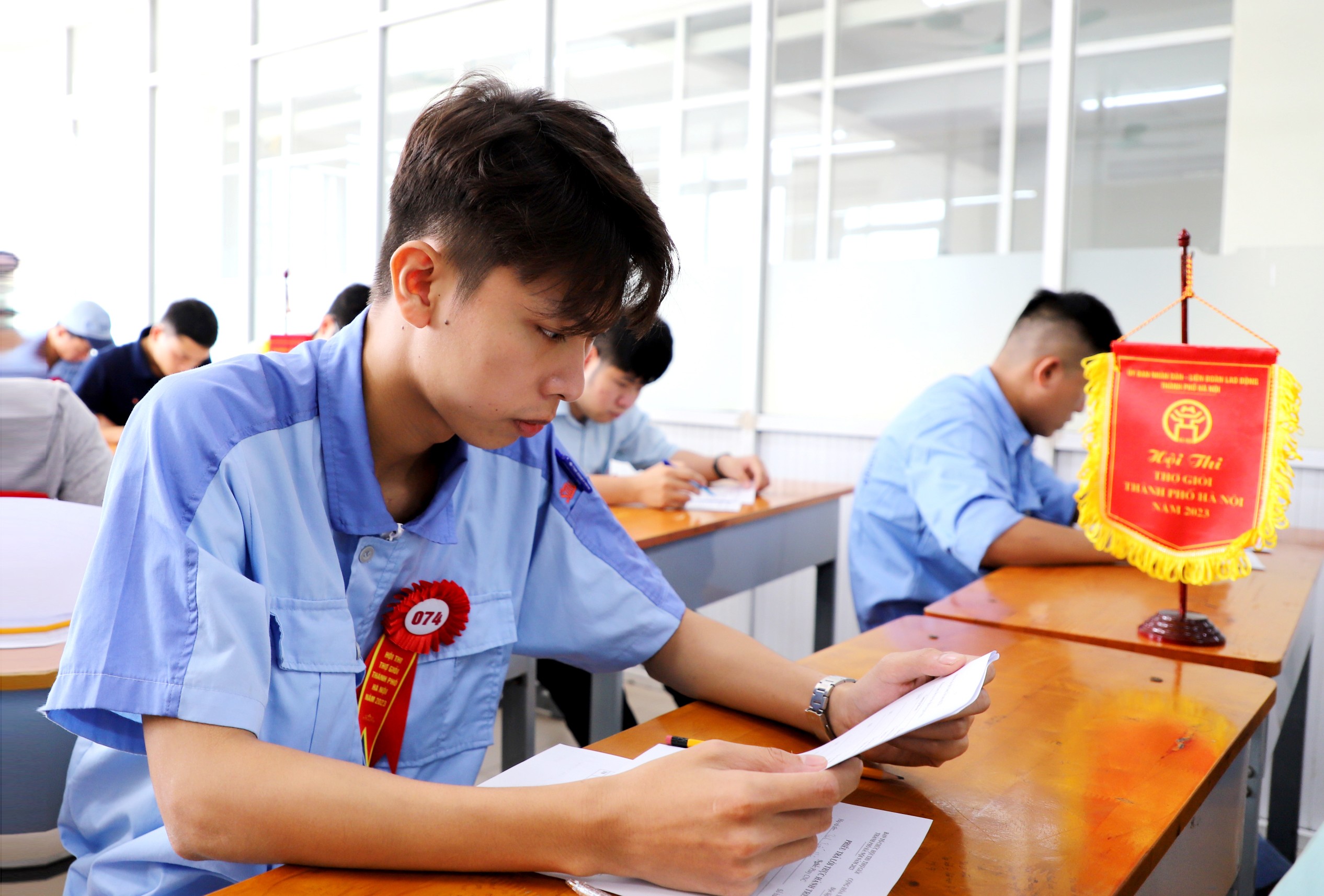Công nhân Trịnh Tuấn Hưng đến từ Công ty TNHH Điện Stanley Việt Nam đang tập trung làm bài thi thực hành trên giấy nội dung Phay CNC tại Hội thi thợ giỏi thành phố Hà Nội năm 2023.