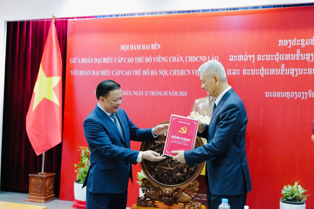 Bí thư Thành ủy Hà Nội Đinh Tiến Dũng trao tặng Thành ủy Viêng Chăn bộ tài liệu tham khảo về công tác xây dựng Đảng và hệ thống chính trị.