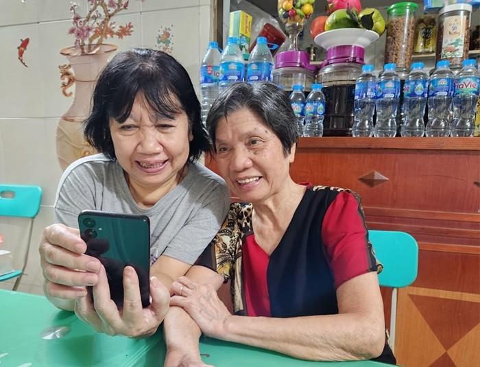 Niềm vui của bà Đặng Thị Thuận (trái) khi nhận thông báo lương hưu qua tài khoản - Ảnh: T.Anh