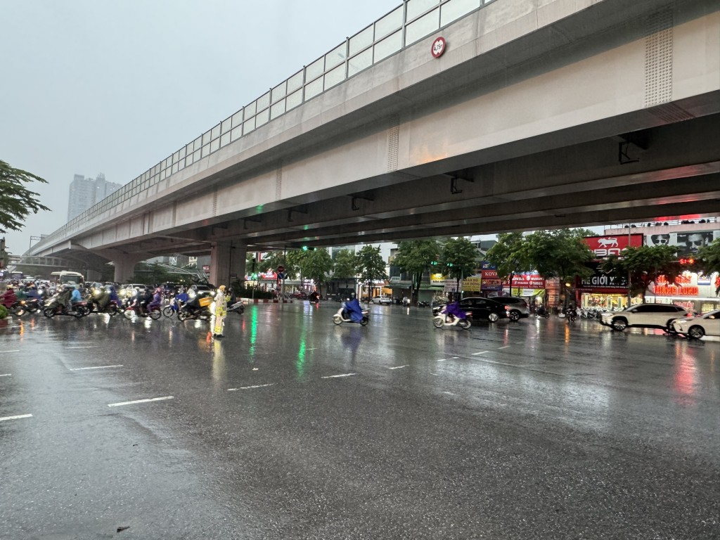 Cảnh sát giao thông dầm mưa giúp đỡ người dân di chuyển qua các điểm úng ngập