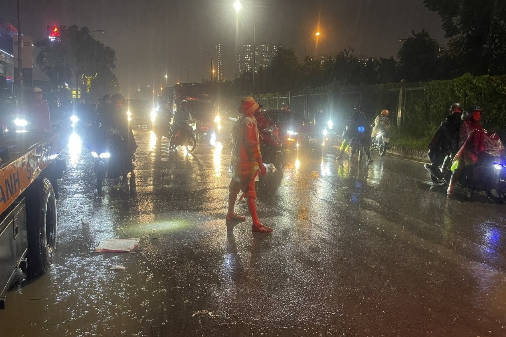 Cảnh sát giao thông dầm mưa giúp đỡ người dân di chuyển qua các điểm úng ngập