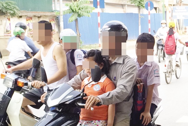 Phụ huynh kẹp 3 trước cửa trường tiểu học tại Hà Nội trong khi học sinh không đội mũ bảo hiểm (ảnh: Hạnh Nguyên)