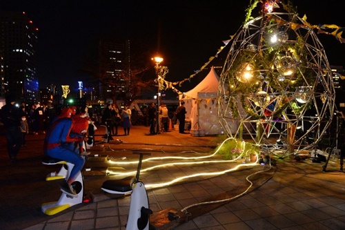 People wearing spiderman costunes pedal to generate electricity to light LED lights of a mirror ball inside an art installation during the Earth Hour environmental campaign event in suburban Tokyo on March 29, 2014.
