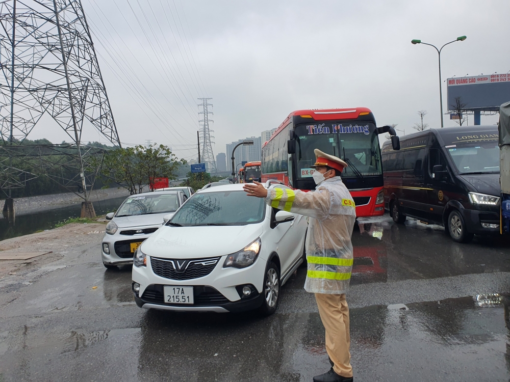 Cảnh sát giao thông đội mưa rét điều tiết giao thông cho dòng phương tiện chen chúc đổ về Thủ đô