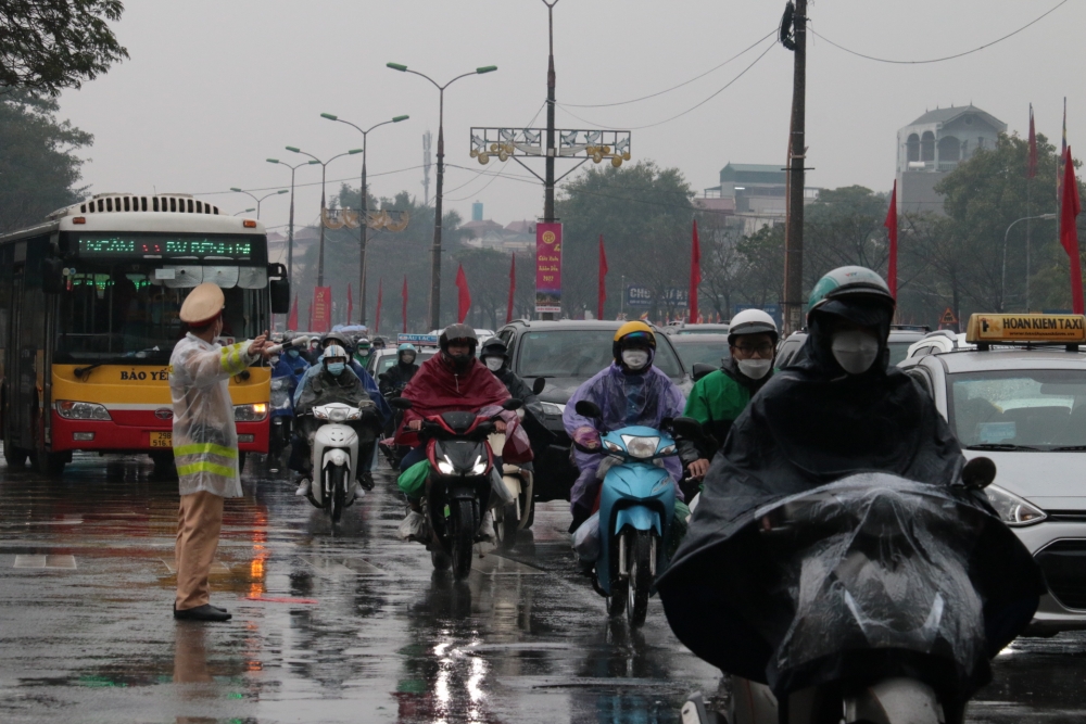Cảnh sát giao thông đội mưa rét điều tiết giao thông cho dòng phương tiện chen chúc đổ về Thủ đô