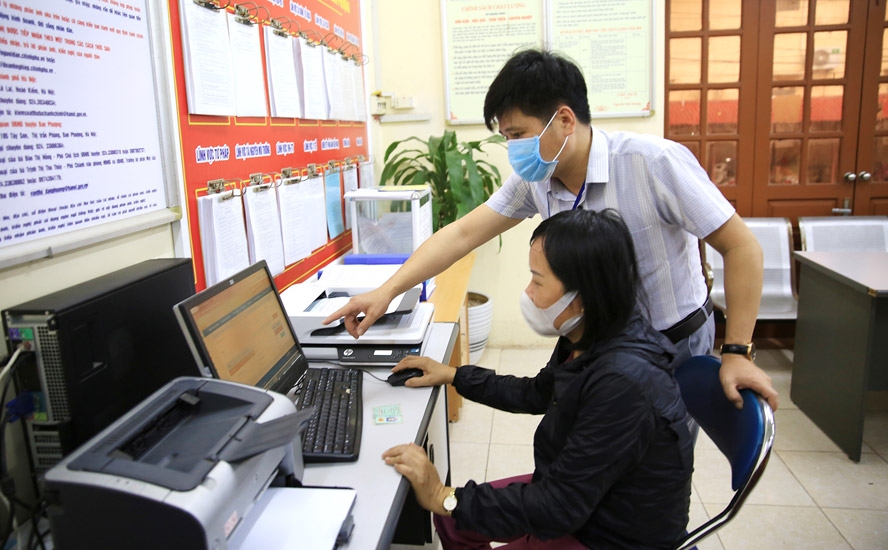 Cán bộ hướng dẫn người dân làm thủ tục dịch vụ công trực tuyến tại Bộ phận một cửa huyện Đan Phượng. (Ảnh: Nguyễn Quang)