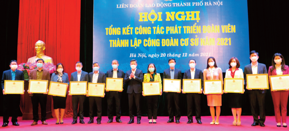 Bà Nguyễn Thị Kim Dung - Chủ tịch LĐLĐ quận Hai Bà Trưng (người mặc áo vàng, đứng giữa) nhận Bằng khen của LĐLĐ thành phố Hà Nội về công tác phát triển đoàn viên năm 2021.