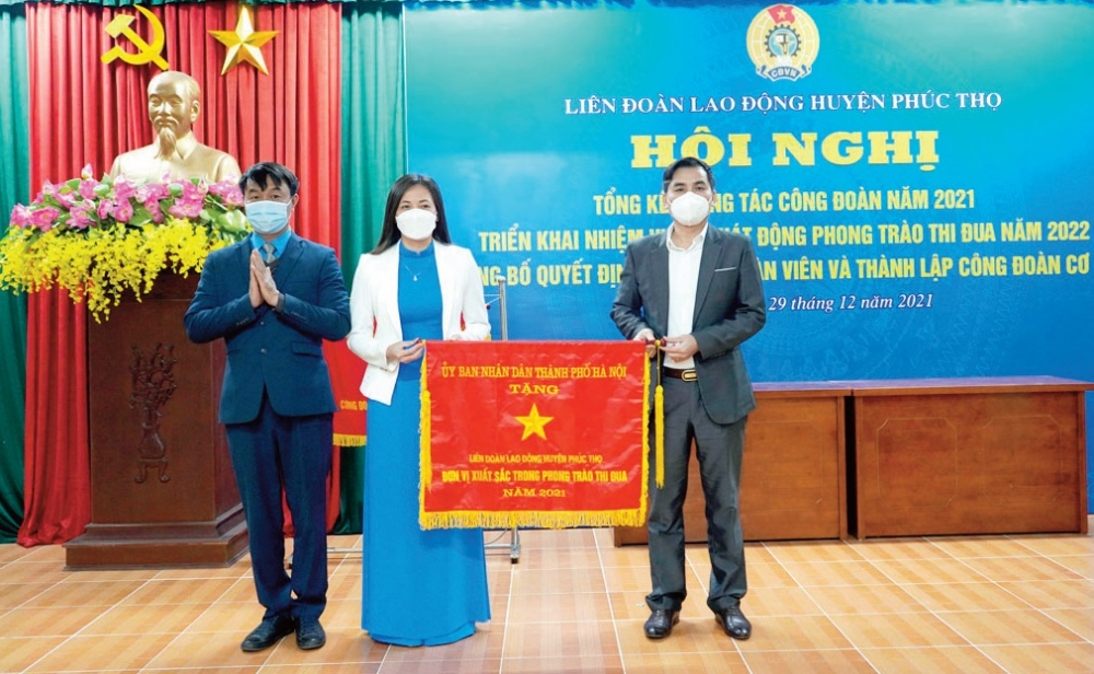Lãnh đạo LĐLĐ huyện Phúc Thọ đón nhận Cờ đơn vị thi đua xuất sắc năm 2021 của Ủy ban nhân dân thành phố Hà Nội. 	Ảnh: Mai Quý